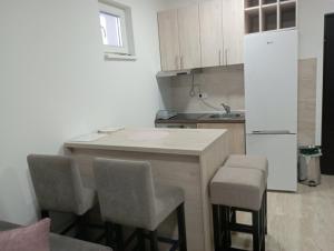 a kitchen with a counter with stools and a refrigerator at Apartmani Marija in Vrdnik