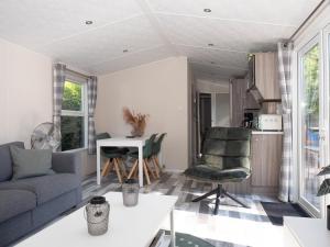 een woonkamer met een bank en een tafel bij Luxury chalet on cozy family campsite. in Garderen