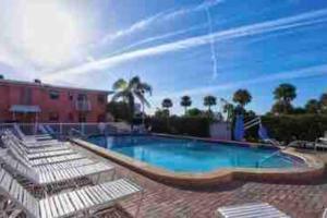 a swimming pool with lounge chairs next to a building at Gorgeous Beach view balcony with heated pool in St Pete Beach