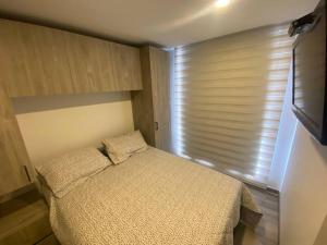 a bedroom with a bed and a window with blinds at Inside the heart of Bogota in Bogotá