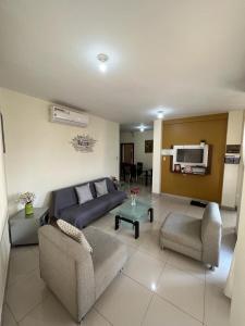 a living room with a couch and chairs and a tv at Garzota Suites Airport Balcony in Guayaquil