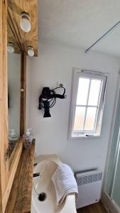 baño con lavabo, espejo y ventana en La Casa De Lylou location de bungalows, en Lavos