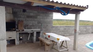 une cuisine extérieure avec une table et un banc dans l'établissement Sobradinho Nova Torres, 