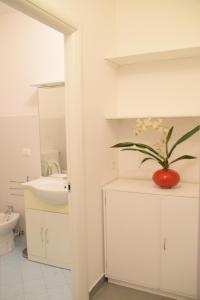 uma casa de banho com um lavatório e um vaso com flores no balcão em Loft in centro con parcheggio em Trieste