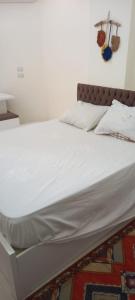 a bed with white sheets and pillows on it at Casablanca Beach for families and couples only in Hurghada