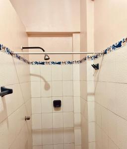 y baño con ducha y azulejos azules y blancos. en Hotel Juan Diego Pucallpa, en Pucallpa