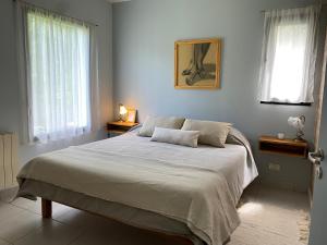 a bedroom with a large bed with two windows at Kalimera in Lago Puelo