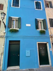 un edificio azul con dos puertas y dos ventanas en CIOSOT HOUSE, en Chioggia