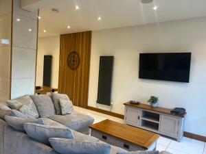 a living room with a couch and a flat screen tv at Broadway Beach Home with Hot tub in Herne Bay