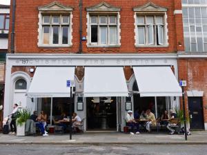 people sitting outside of a restaurant with white awnings at Bright one bedroom apartment in Chiswick in London