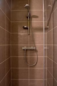 eine Dusche mit Duschkopf an einer gefliesten Wand in der Unterkunft Maison meublée Divonne-les-Bains in Divonne-les-Bains