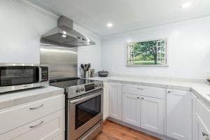 La cuisine est équipée de placards blancs et d'un four micro-ondes. dans l'établissement Laurelhurst - Cozy 1 Bedroom Apt Near Children’s Hospital and UW, à Seattle