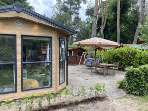 Casa pequeña con mesa y sombrilla en Luxury chalet on cozy family campsite. en Garderen