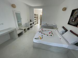 Ascot Watamu في واتامو: غرفة نوم بيضاء مع سرير مع ديكور زهرة عليه