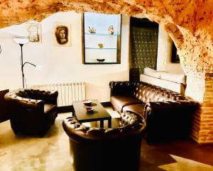 a living room with leather couches and a table at Casa cueva El Nido Casa Rural in Casas de los Teatinos