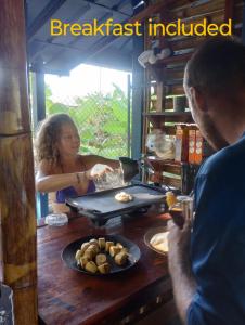 une femme préparant la nourriture à une table avec une assiette de nourriture dans l'établissement Ferdinand the bull hostel, à Pedasí Town