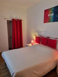 1 dormitorio con 1 cama blanca grande con cortina roja en Au Petit Ronceraie en Blois