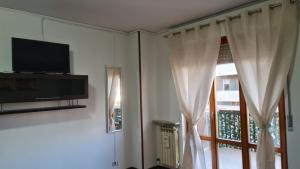 salon z telewizorem i oknem w obiekcie Appartamento Verona in w Weronie