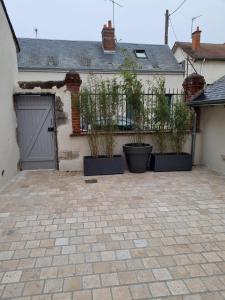 a house with three potted plants in front of a garage at Au Petit Ronceraie in Blois