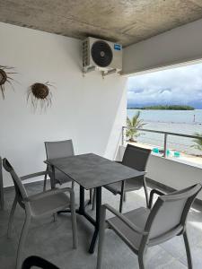 una mesa y sillas en un balcón con vistas al océano en Pension Irivai, appartement UO UO 3 chambres vue mer en Uturoa