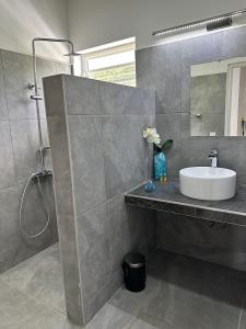 La salle de bains est pourvue d'un lavabo et d'un miroir. dans l'établissement Pension Irivai, appartement UO UO 3 chambres vue mer, à Uturoa