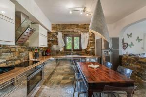 uma cozinha com uma mesa de madeira e uma parede de pedra em Efharis Beachfront Villa em Platamon