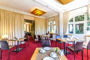 a restaurant with tables and chairs and windows at Hotel Villa Elben Lörrach bei Basel in Lörrach