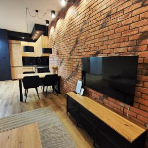 a living room with a brick wall and a large flat screen tv at Asti Apartamenty Centrum Stargard in Stargard