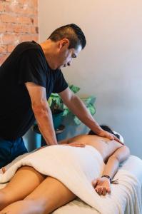 un hombre recibiendo un masaje de una mujer en una cama en Selina San Jose, en San José