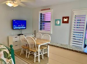 Un comedor con mesa y sillas y un televisor. en Ocean view studio with heated pool, en St Pete Beach