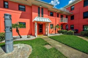 un edificio rojo con un patio de césped delante de él en Ocean view studio with heated pool, en St Pete Beach