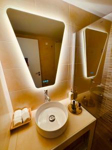 uma casa de banho com um lavatório e um espelho grande em Blue Horizon Gem On The Port em Rafina