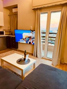 a living room with a couch and a tv at Blue Horizon Gem On The Port in Rafina