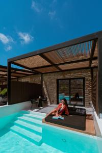 a woman sitting on a bench next to a swimming pool at Ftelia Black Villas in Elia