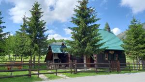 Cabaña de madera con techo verde y valla en Family Farm Apartments, en Žabljak
