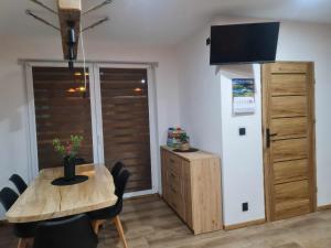a dining room with a wooden table and a television at Apartamenty Quattro in Stronie Śląskie