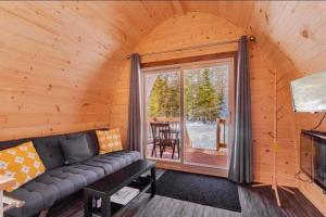 a living room with a couch and a large window at Chalet Alice à louer avec Spa Mauricie in Saint-Alexis-des-Monts
