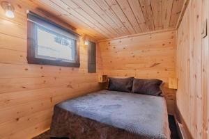 a bed in a log cabin with a window at Chalet Alice à louer avec Spa Mauricie in Saint-Alexis-des-Monts