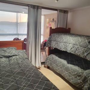 sypialnia z 2 łóżkami i oknem w obiekcie Departamento en Condominio privado Costa Pingueral w mieście Concepción