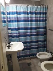 a bathroom with a shower curtain and a sink and a toilet at Departamentos calle 8 in Necochea