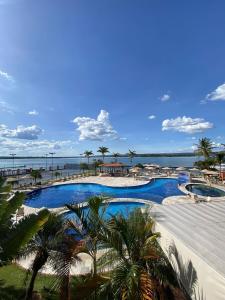 a resort swimming pool with palm trees and the ocean at Flat 127 à 5 min da esplanada in Brasilia