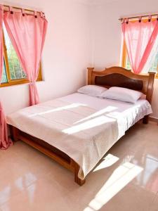 a bedroom with a large bed with pink curtains at Finca Villa Sophia! in Quimbaya