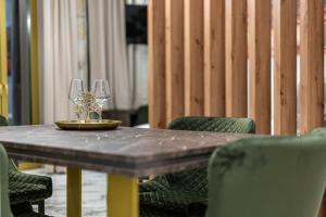 a wooden table with two wine glasses on it at Royal Gold City Suites by Estia in Heraklio Town