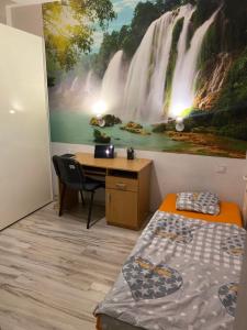 a bedroom with a desk and a waterfall mural on the wall at Vlastná izba 5min od letiska in Bratislava