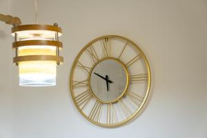 un reloj colgando de una pared con una lámpara de araña en Apartament Lucas, en Brad