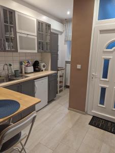 a kitchen with gray cabinets and a table and a door at Várfal apartman in Kőszeg