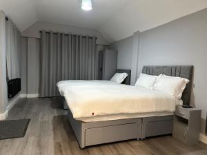 um quarto com uma cama grande e lençóis brancos em Ruxley Studios em Orpington