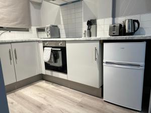 uma cozinha com armários brancos e piso em madeira em Ruxley Studios em Orpington