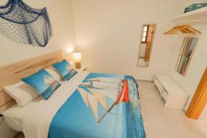 Schlafzimmer mit einem Bett mit blauen und weißen Kissen in der Unterkunft Agüita Surf Lodge in Las Palmas de Gran Canaria