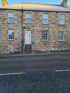 a brick building with a white door and stairs at Cullen Holiday Home in Cullen